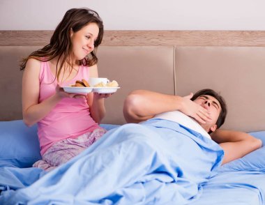 Mutlu bir aile yatakta kahvaltı yapıyor.