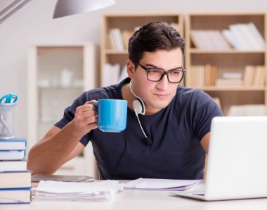 Genç öğrenci fincandan kahve içiyor.