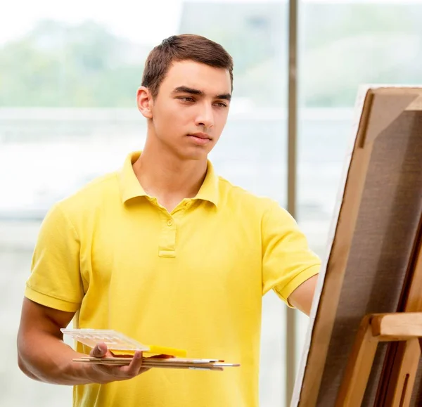 Mladý umělec kreslí obrázky ve světlém studiu — Stock fotografie