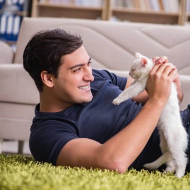 Yakışıklı delikanlı beyaz yavru kedi ile oynarken