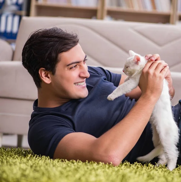 Yakışıklı delikanlı beyaz yavru kedi ile oynarken