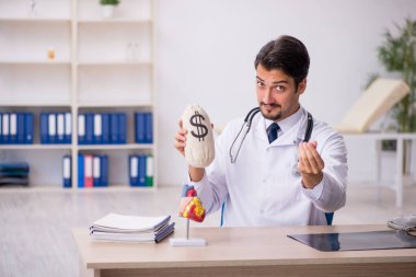 Genç erkek doktor kardiyolog para çantası tutuyor.