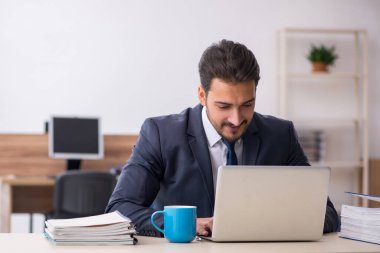 Genç erkek çalışan işyerinde oturuyor.