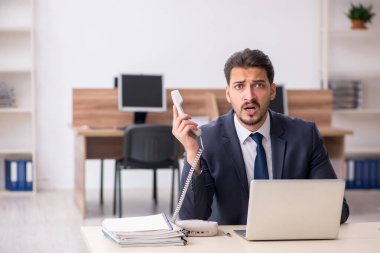 Genç erkek çalışan işyerinde oturuyor.