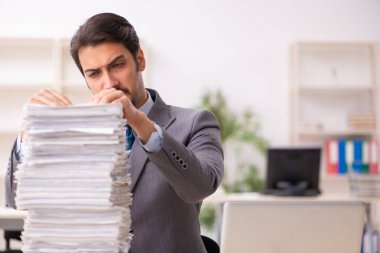 Ofisteki aşırı işten memnun olmayan genç bir erkek işçi.