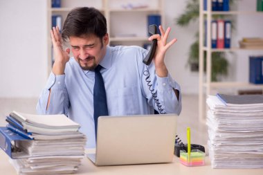 Genç bir erkek çalışan ve ofiste çok fazla iş var.