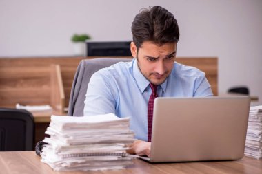 Ofisteki aşırı işten memnun olmayan genç bir erkek işçi.