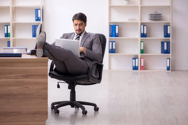 Jovem atraente masculino empregado sentado no local de trabalho — Fotografia de Stock