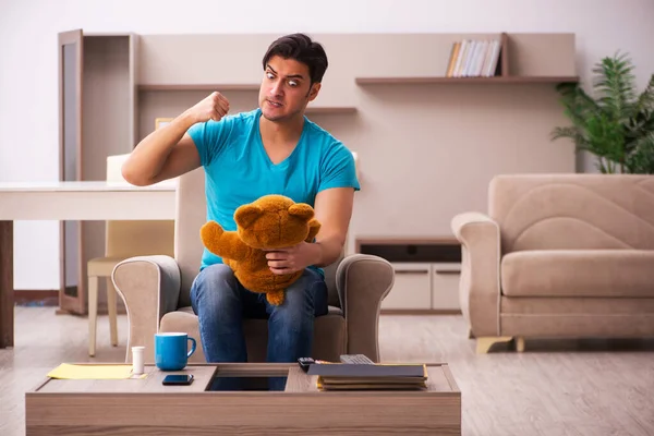 Joven sentado con oso juguete en casa — Foto de Stock
