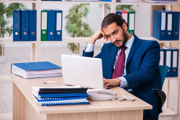 Ung manlig anställd och för många arbetar på kontoret — Stockfoto
