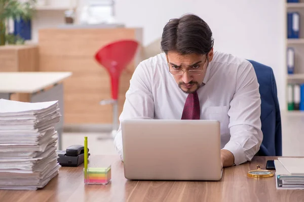 Ung manlig anställd och för mycket arbete på kontoret — Stockfoto