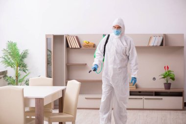Young male contractor disinfecting at home