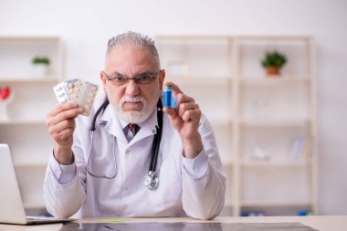 Klinikte çalışan yaşlı erkek doktor.