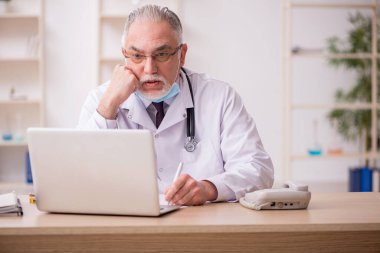 Yaşlı erkek doktor salgın sırasında klinikte çalışıyor.