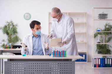 Salgın sırasında laboratuvarda çalışan iki erkek kimyager.