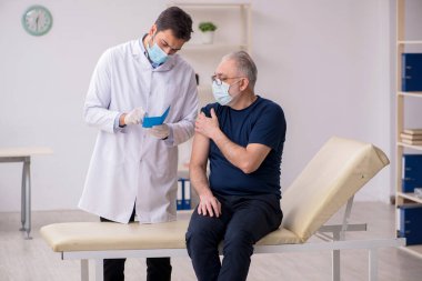 Yaşlı bir erkek hasta aşıyla genç bir doktoru ziyaret ediyor.