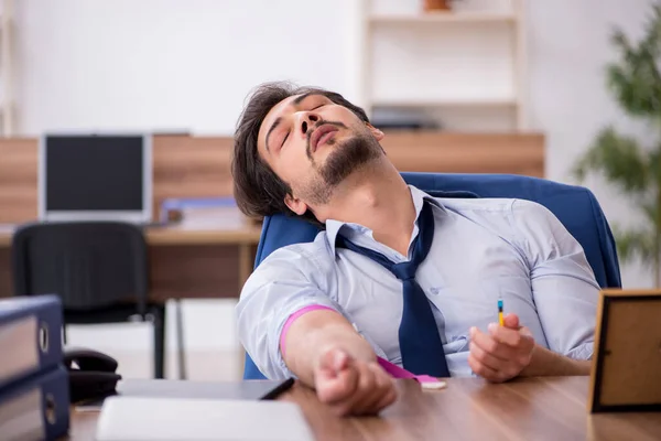 Giovane dipendente tossicodipendente maschile sul posto di lavoro — Foto Stock