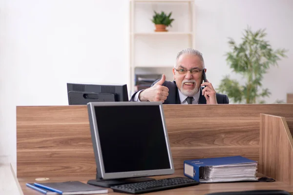 Ältere männliche Mitarbeiter sitzen am Arbeitsplatz — Stockfoto
