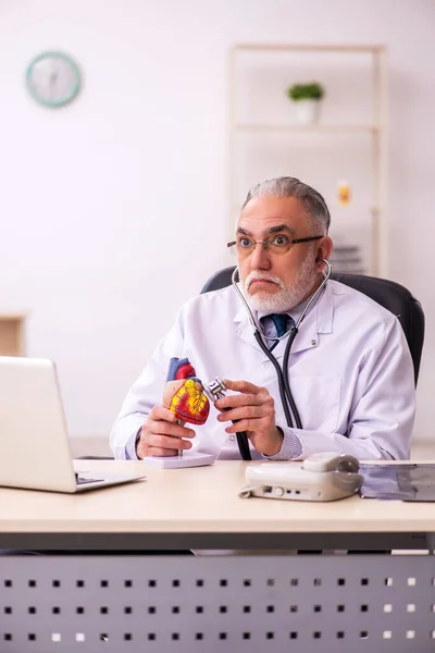 Verouderde mannelijke arts cardioloog werkzaam in de kliniek — Stockfoto