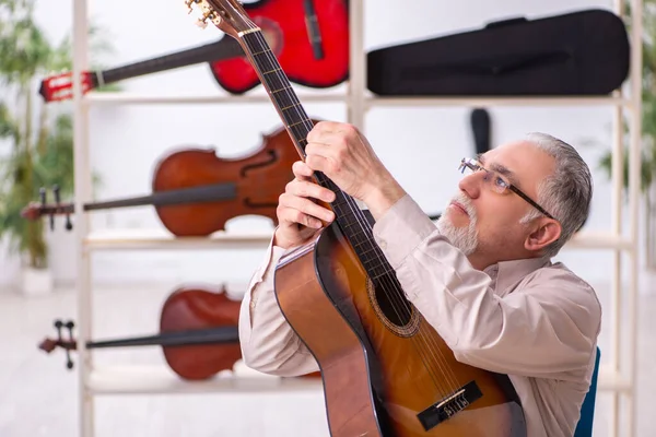 Old male repairman repairing musical instruments at workplace — Stock Photo, Image