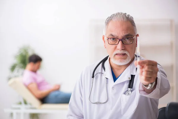 Viejo médico y joven paciente masculino en concepto de vacunación —  Fotos de Stock