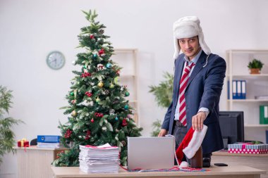 Genç erkek çalışan ofiste yeni yılı kutluyor.