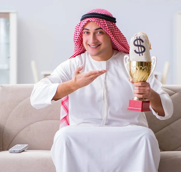 Hombre árabe con premio y dinero en el sofá — Foto de Stock
