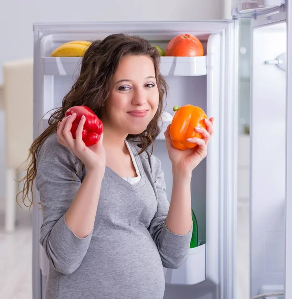 Donna incinta vicino al frigorifero in cerca di cibo e snack — Foto Stock