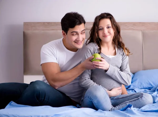 Jonge familie met zwangere vrouw verwacht baby in bed — Stockfoto