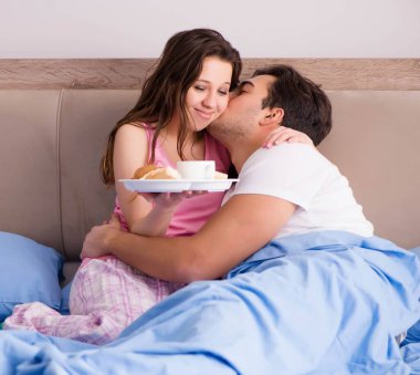 Mutlu bir aile yatakta kahvaltı yapıyor.