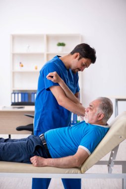 Yaşlı erkek hasta genç erkek doktoru ziyaret ediyor.