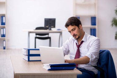 Ofisteki aşırı işten memnun olmayan genç bir erkek işçi.