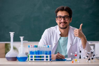 Tahtanın önündeki genç erkek kimyager.