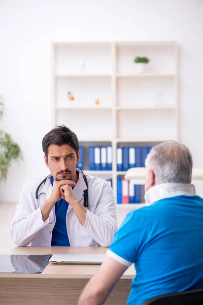 Velho pescoço ferido paciente masculino visitando jovem médico masculino — Fotografia de Stock