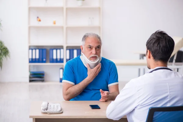 Stary kark ranny mężczyzna pacjent odwiedza młodego lekarza płci męskiej — Zdjęcie stockowe