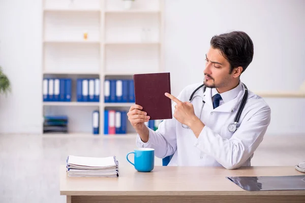 Klinikte kitap okuyan genç bir erkek doktor. — Stok fotoğraf