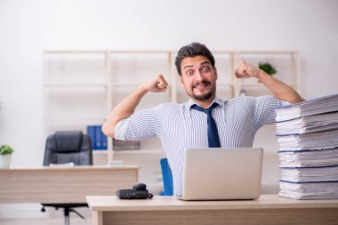 Genç bir erkek çalışan ve ofiste çok fazla iş var.