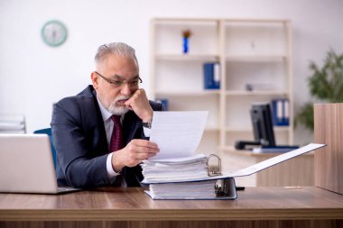 Ofiste çalışan yaşlı bir erkek.