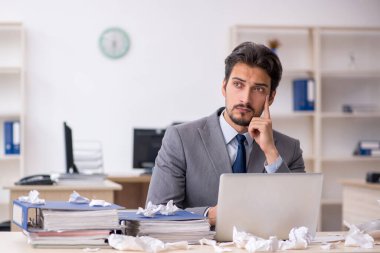 Genç bir erkek çalışan ve ofiste çok fazla iş var.