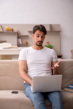 Genç erkek öğrenci salgın sırasında evde çalışıyor.