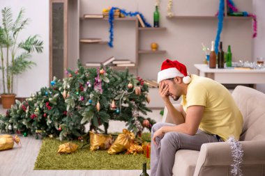 Genç adam Noel partisinden sonra daireyi temizliyor.