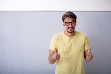 Beyaz tahtanın önünde genç bir erkek öğrenci.