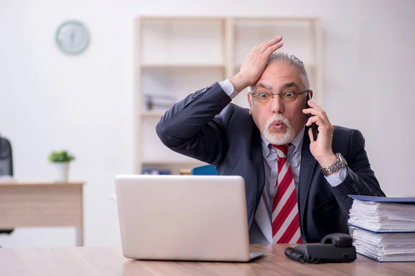 Oude mannelijke werknemer die op kantoor werkt — Stockfoto