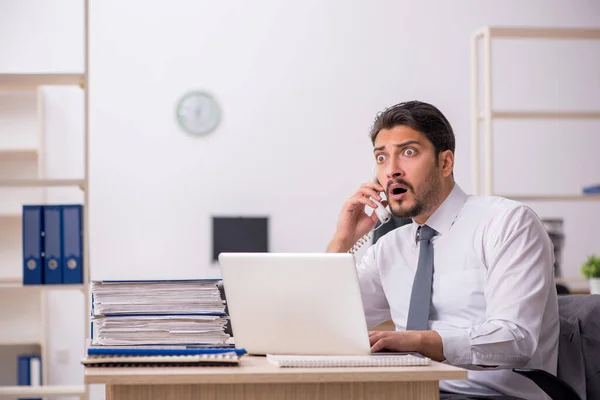 Ung manlig anställd och för mycket arbete på kontoret — Stockfoto