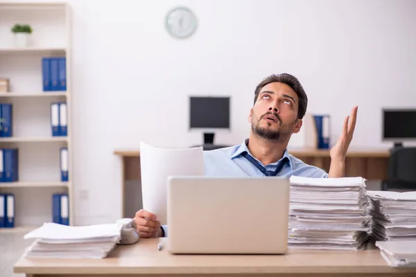 Joven empleado masculino y demasiado trabajo en la oficina — Foto de Stock