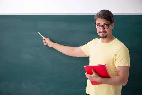 Jovem estudante do sexo masculino na frente do quadro negro — Fotografia de Stock