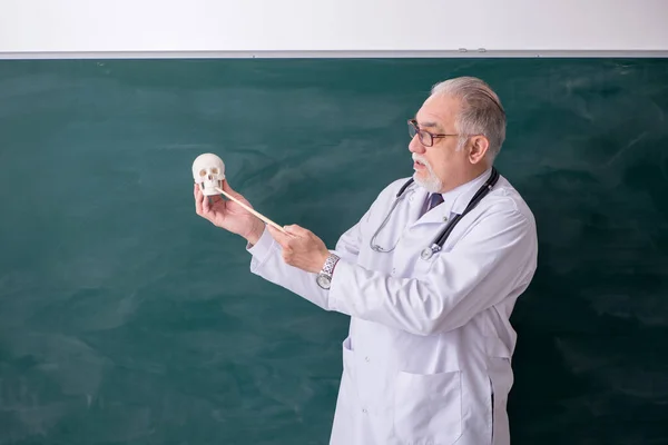 Starý muž lékař učitel před tabulí — Stock fotografie