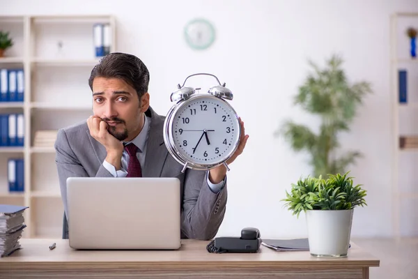 Joven empleado masculino en concepto de gestión del tiempo —  Fotos de Stock