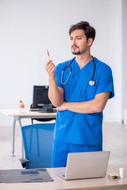 Klinikte çalışan genç erkek doktor.