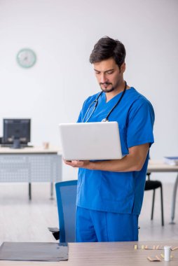 Klinikte çalışan genç erkek doktor.